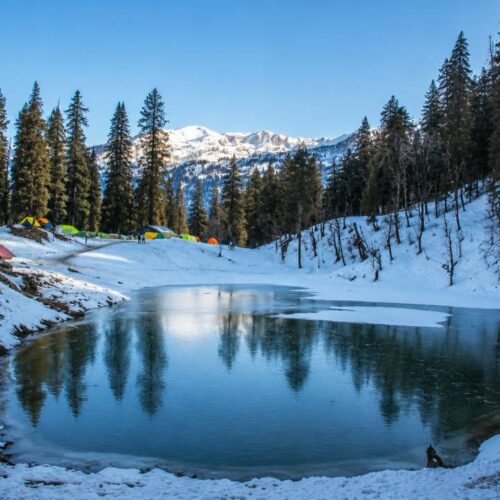 Scenic alpine lake Juda Ka Talab surrounded by dense pine forests on Kedarkantha trek route in Uttarakhand